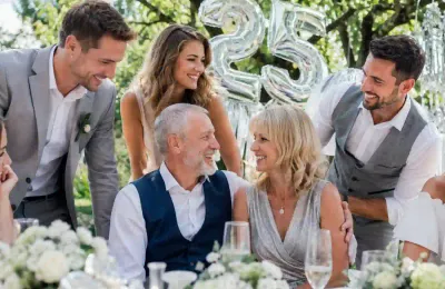 Eine Familie applaudiert einem Paar, das sich bei einer Silberhochzeitsfeier umarmt